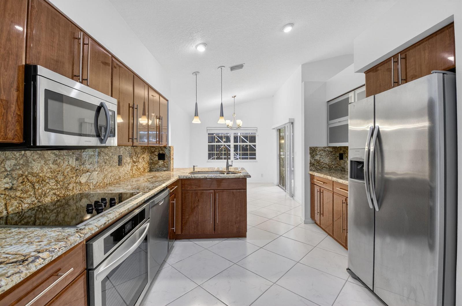 A kitchen with wood cabinets, granite countertops, stainless steel appliances, and white tile flooring — 7558 Ironbridge Circle, Delray Beach FL 33446, DELRAY BEACH, FL