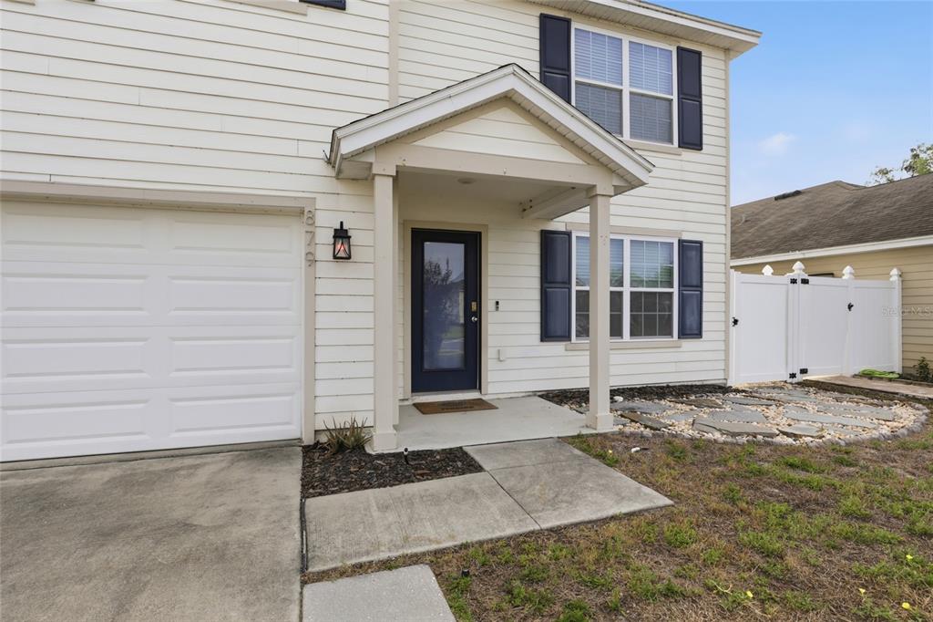A two-story house exterior with white siding, a garage, and a covered front entryway — 879 NW 251ST DRIVE, NEWBERRY, FL