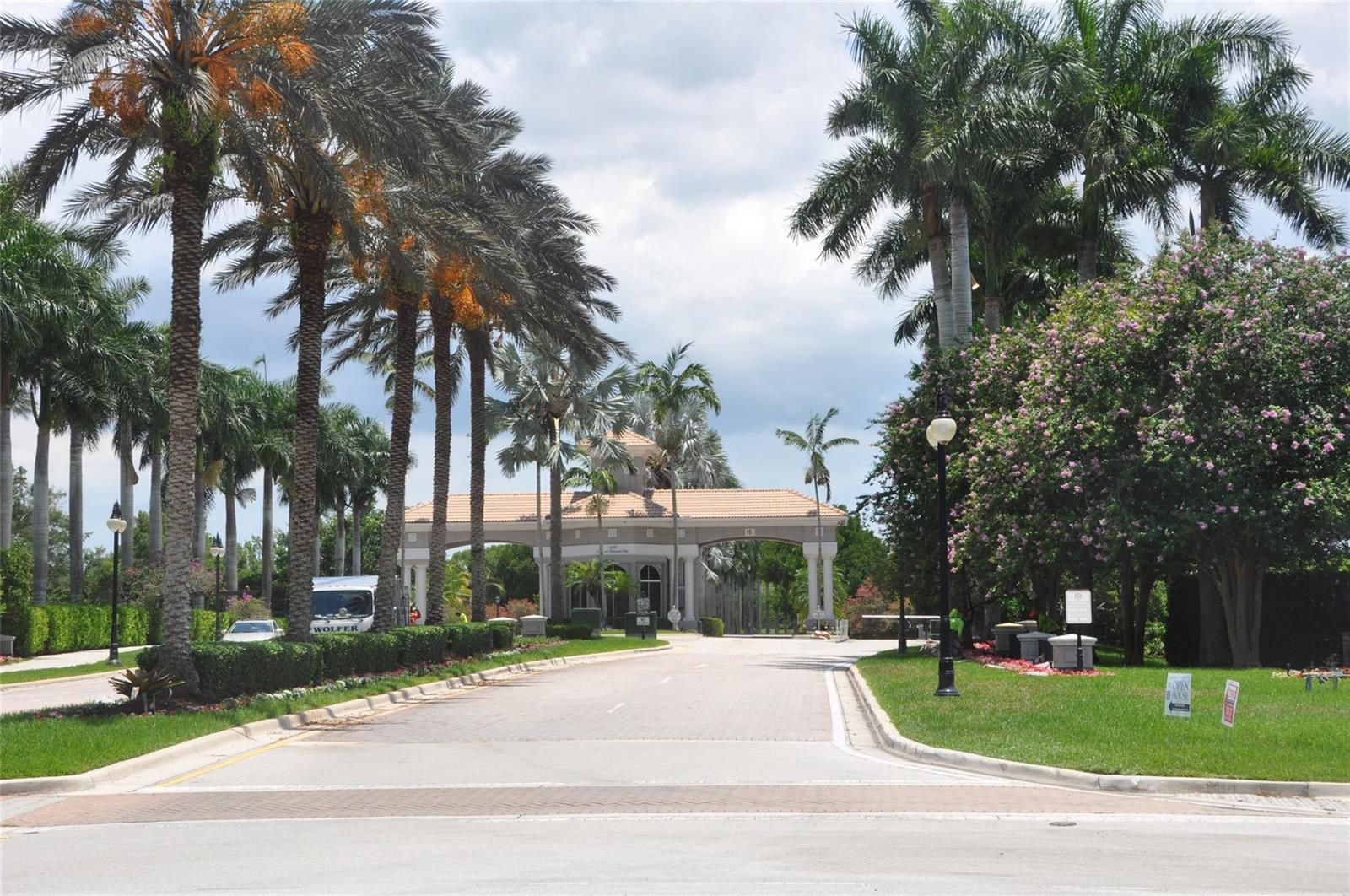 A paved road leads to a gated community entrance with palm trees and a guardhouse — 19496 S Whitewater Avenue, Weston FL 33332, WESTON, FL