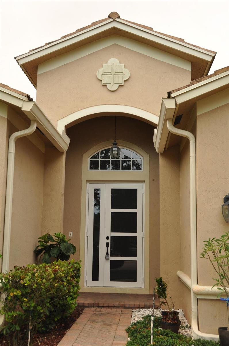 The front entrance of a tan stucco house features a modern door and arched transom — 19496 S Whitewater Avenue, Weston FL 33332, WESTON, FL