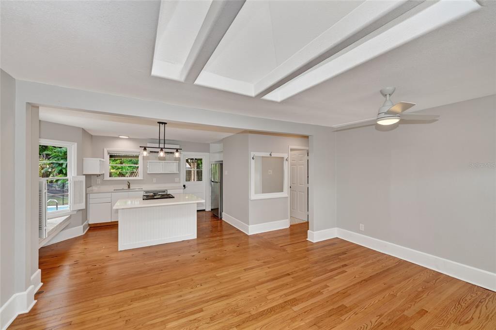 A bright, open-concept kitchen and living area featuring hardwood floors and a white island — 1010 VIRGINIA DRIVE, SARASOTA, FL