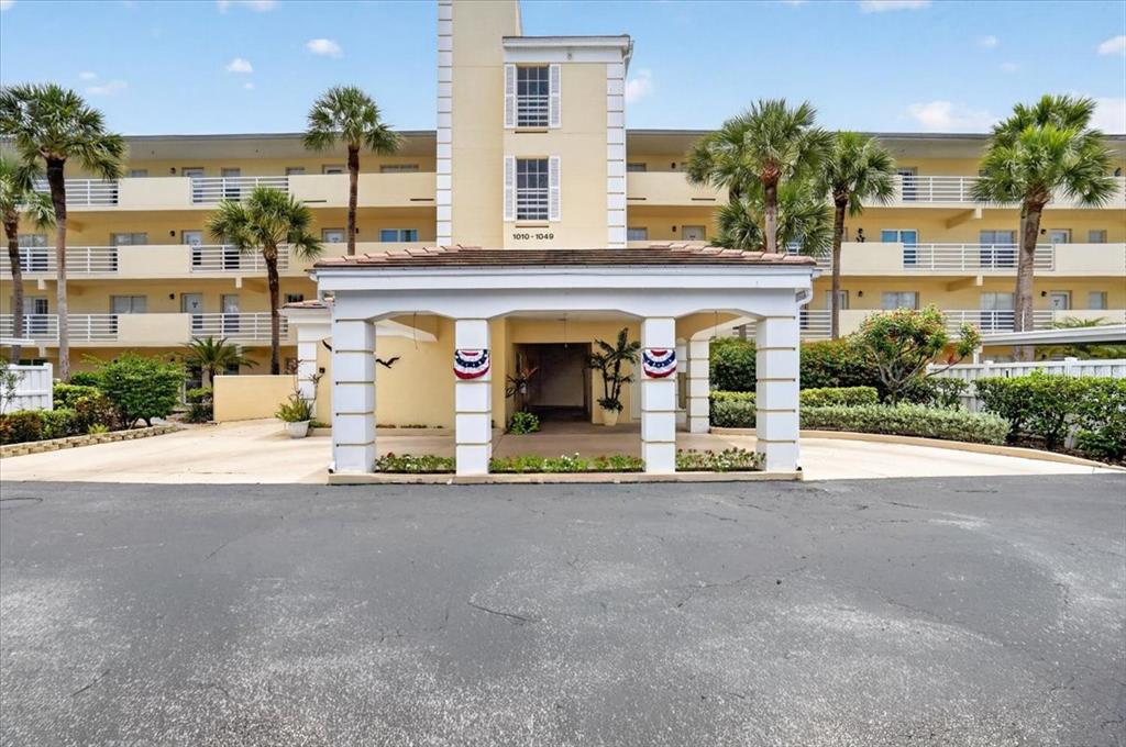 A multi-story apartment building features a covered entrance with white columns and palm trees — 1040 WEXFORD BOULEVARD UNIT 1040, VENICE, FL