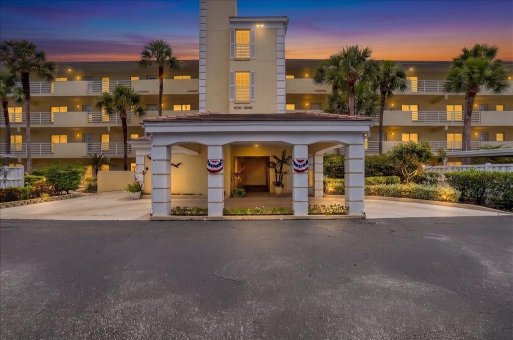 A multi-story apartment building exterior features a covered entrance with columns and palm trees — 1040 WEXFORD BOULEVARD UNIT 1040, VENICE, FL