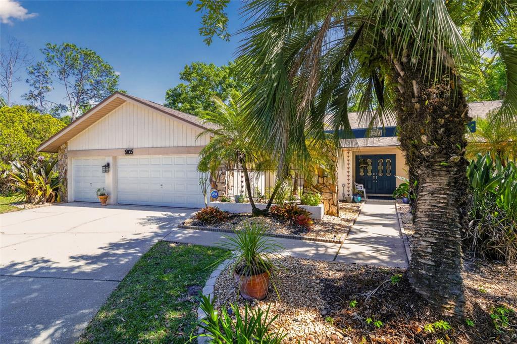 A single-story house with a white garage, stone accents, and a palm tree in front — 5035 BARROWE DRIVE, TAMPA, FL