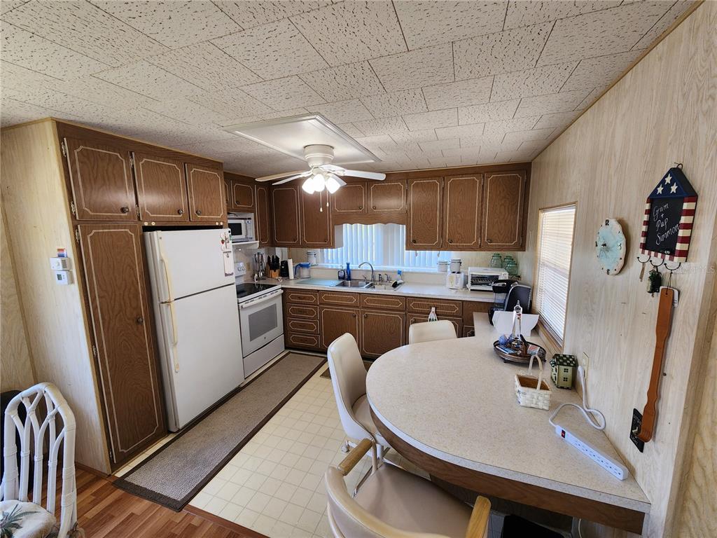 A kitchen features wood cabinets, white appliances, a breakfast bar, and a drop ceiling — 316 DANUBE CIRCLE, BRADENTON, FL