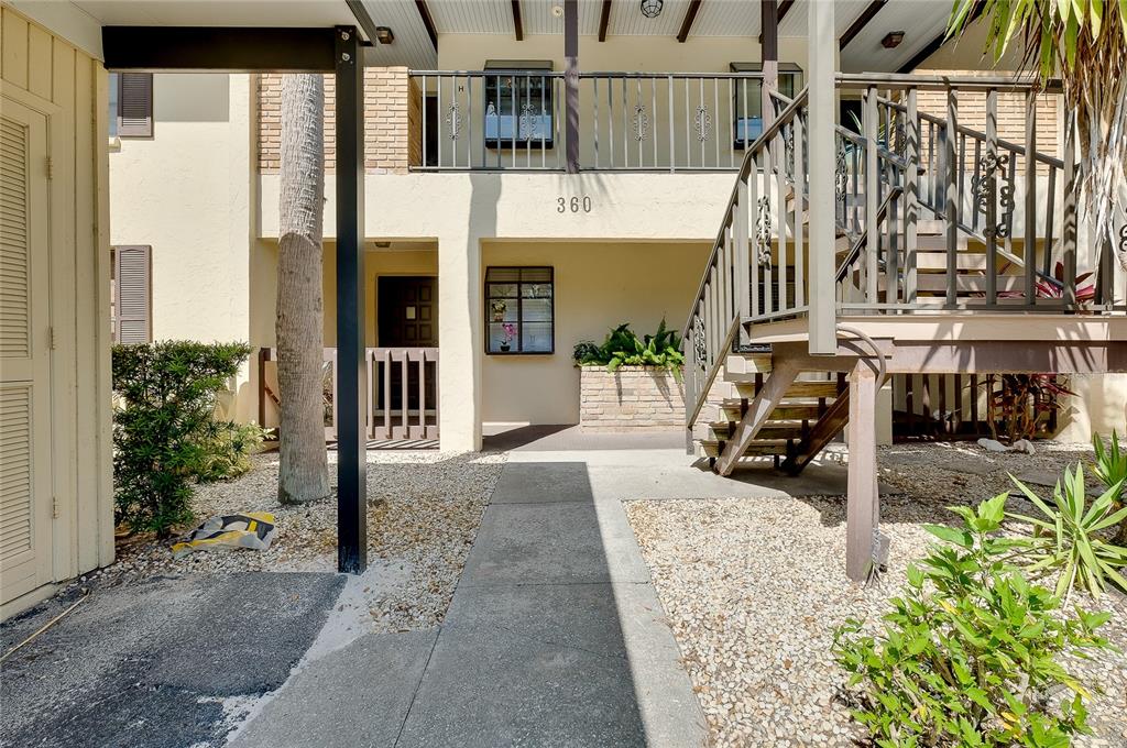A concrete walkway leads to the entrance of a two-story apartment building with stairs — 360 THREE LAKES LANE UNIT E, VENICE, FL