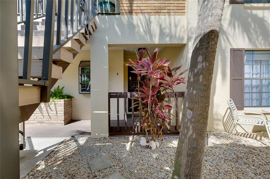 A ground-level apartment entrance features a small patio, a potted plant, and outdoor stairs — 360 THREE LAKES LANE UNIT E, VENICE, FL