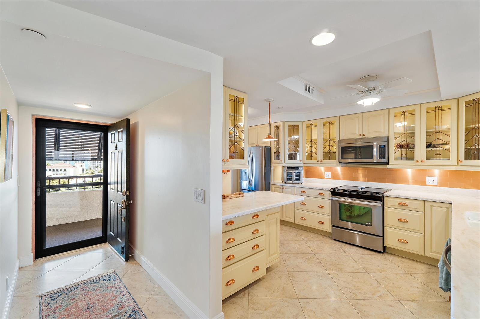 A kitchen with cream-colored cabinets, stainless steel appliances, and a balcony door entry — 356 Golfview Road # 903, North Palm Beach FL 33408, NORTH PALM BEACH, FL