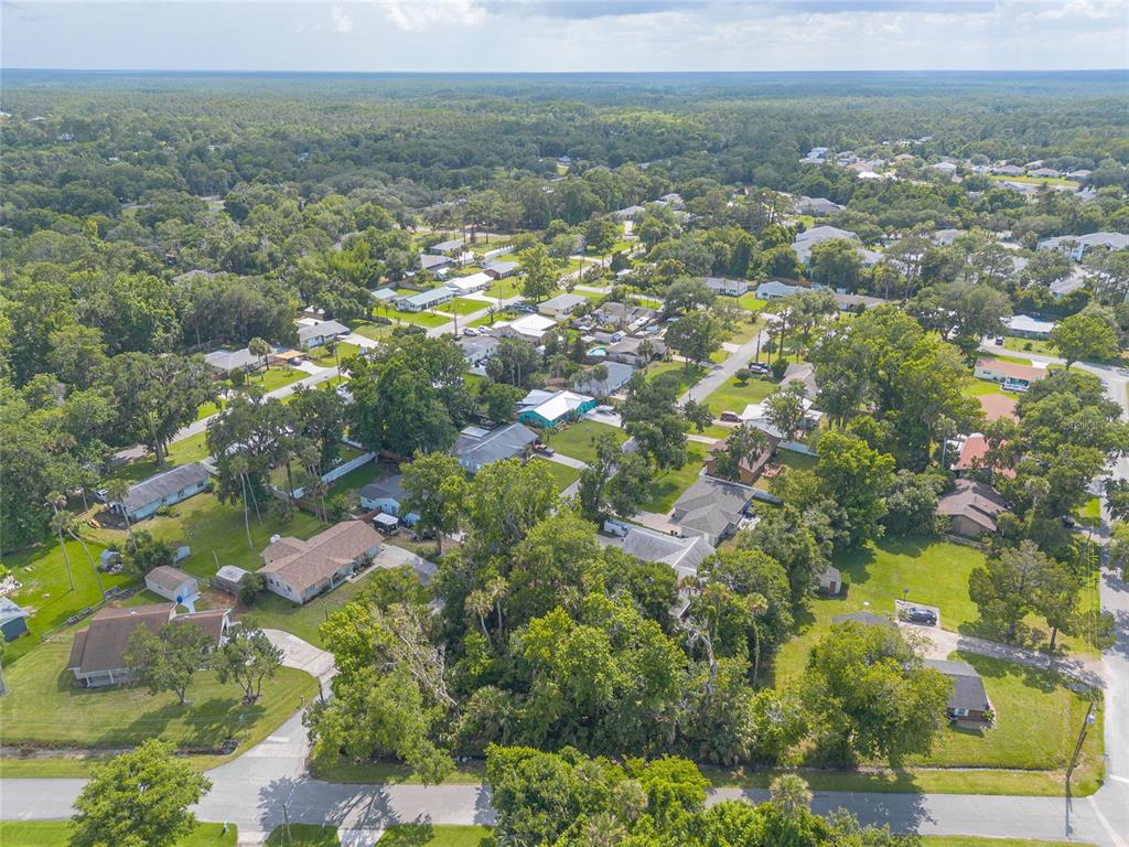 An aerial view shows a residential neighborhood with many trees and single-family homes — 2433 CLAIRE AVENUE, NEW SMYRNA BEACH, FL