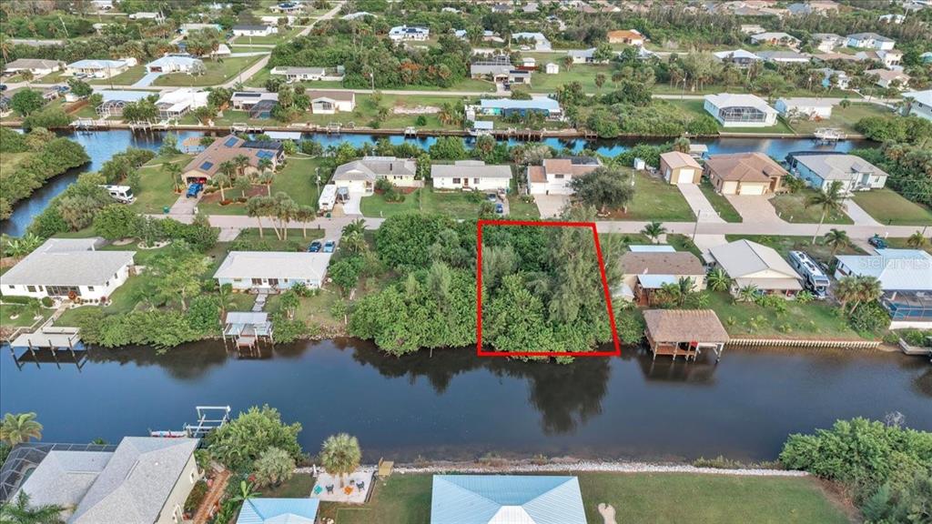 An aerial view shows a vacant, tree-covered waterfront lot outlined in red — 3631 MAGNOLIA WAY, PUNTA GORDA, FL