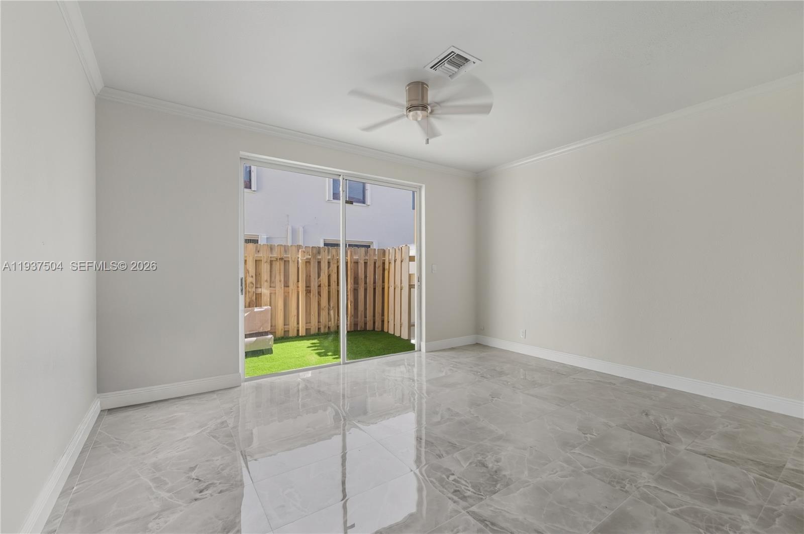 An empty room features gray marble-look tile flooring, a ceiling fan, and a sliding glass door — 810 NE 212th Ter # 5, Miami FL 33179, MIAMI, FL