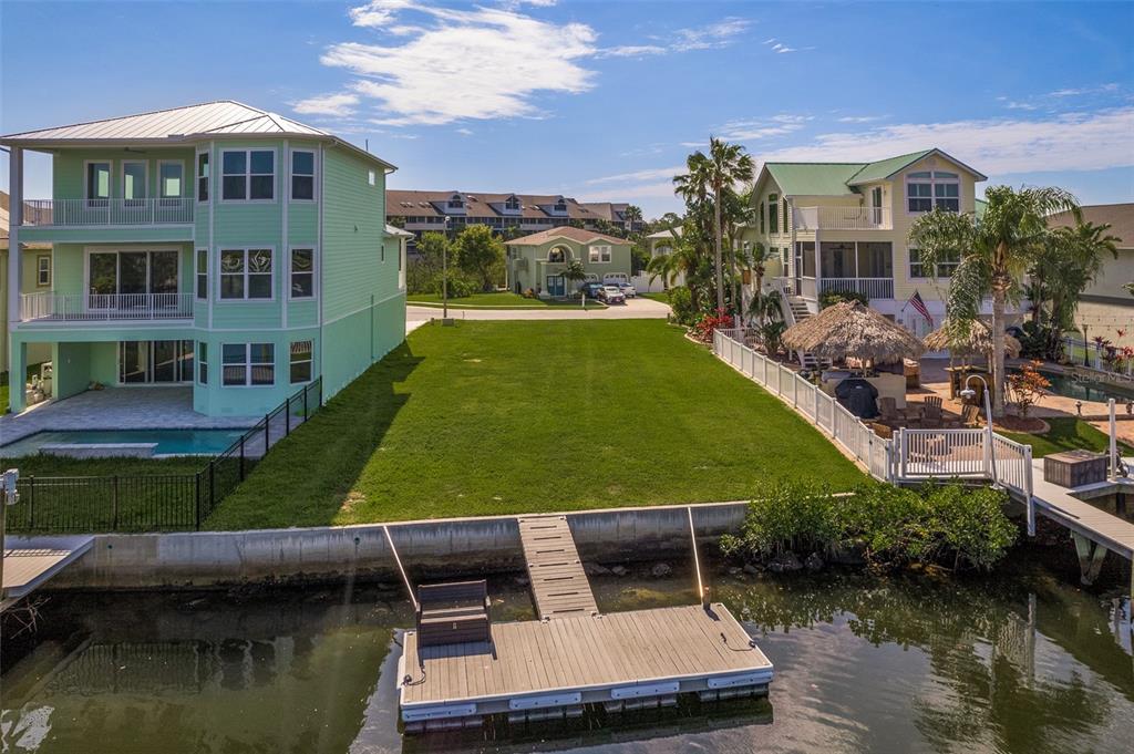 An aerial view of a vacant waterfront lot situated between two large multi-story houses — 5627 JOBETH DRIVE, NEW PORT RICHEY, FL