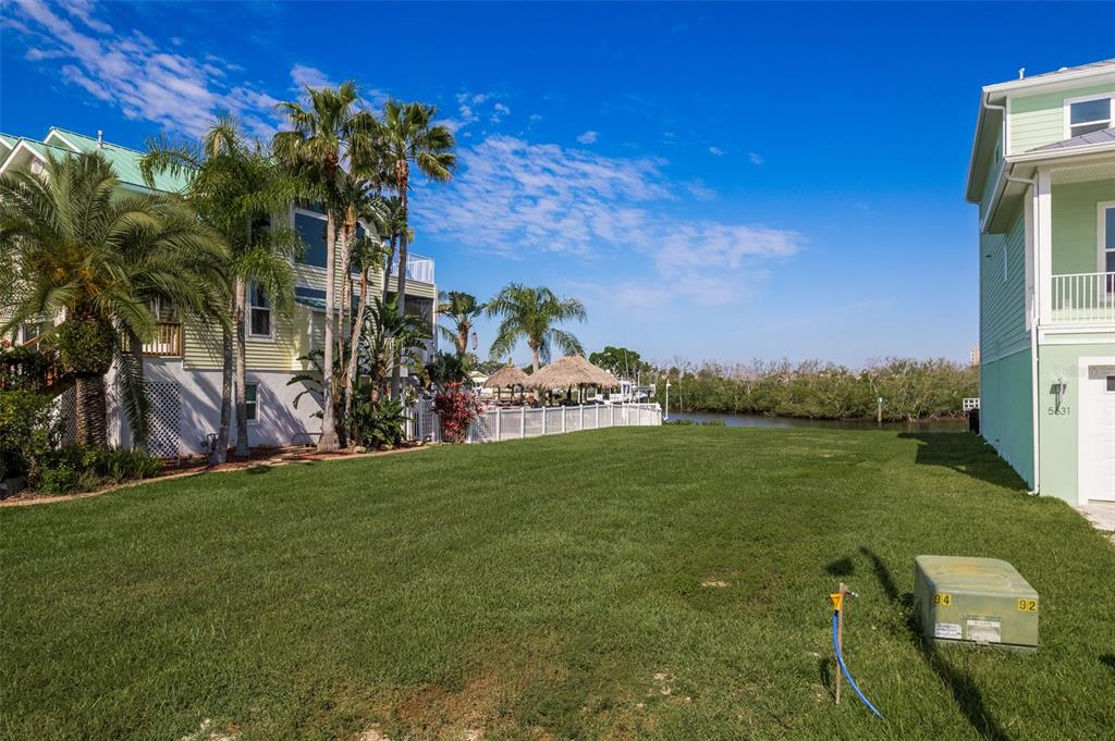 A grassy lot sits between two houses with palm trees and a view of water — 5627 JOBETH DRIVE, NEW PORT RICHEY, FL