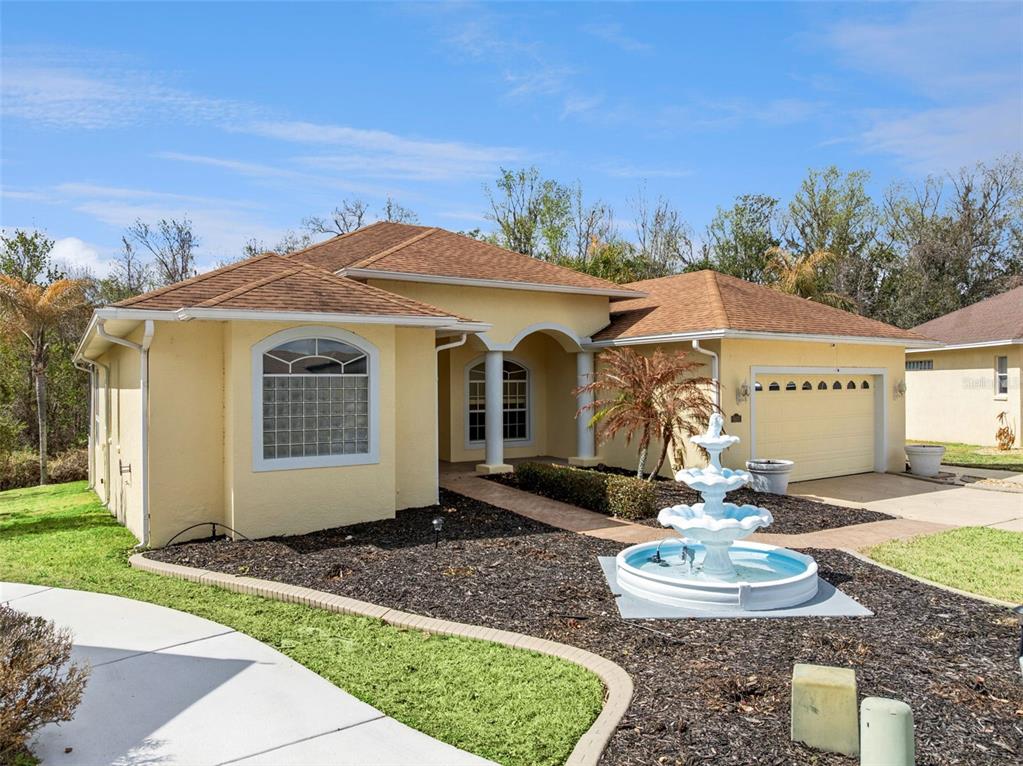 A yellow single-story house with a brown roof, a front fountain, and a two-car garage — 6410 BENDELOW DRIVE, LAKELAND, FL