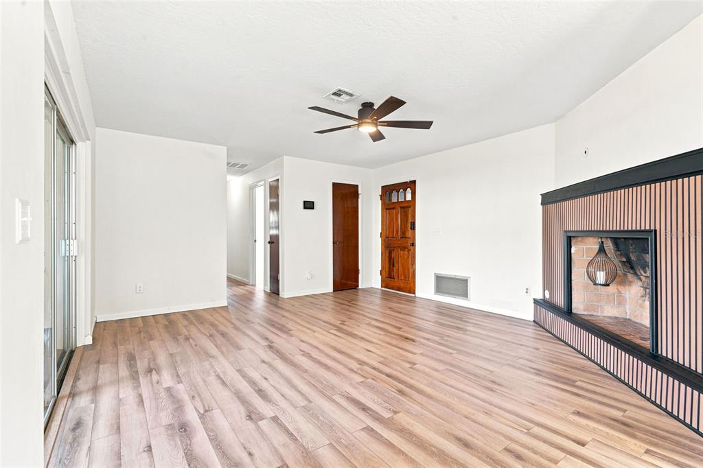 A dining area features light wood-look flooring, two pendant lights, a central window, and sliding doors — 1441 NE OLD MILL DRIVE, DELTONA, FL