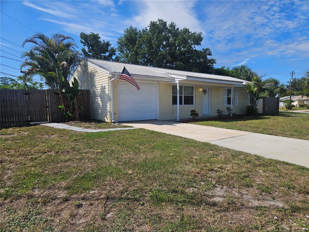 A single-story yellow brick house with a white garage door and an American flag — 7000 BRENTFORD ROAD, SARASOTA, FL