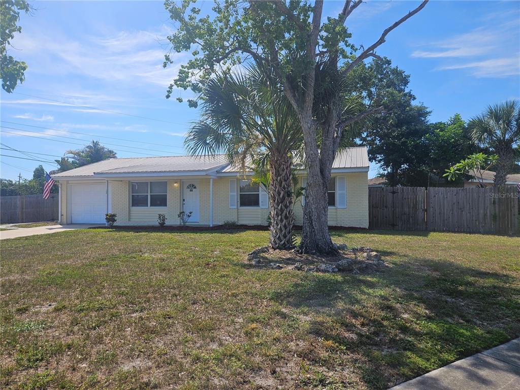 A single-story yellow brick house with a metal roof and a large palm tree — 7000 BRENTFORD ROAD, SARASOTA, FL