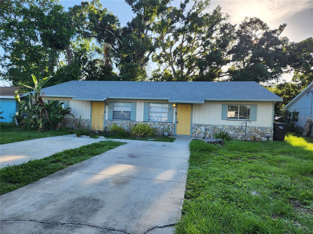 A single-story duplex with yellow doors, stone siding, and a concrete driveway — 1120 36TH STREET W UNIT A, BRADENTON, FL