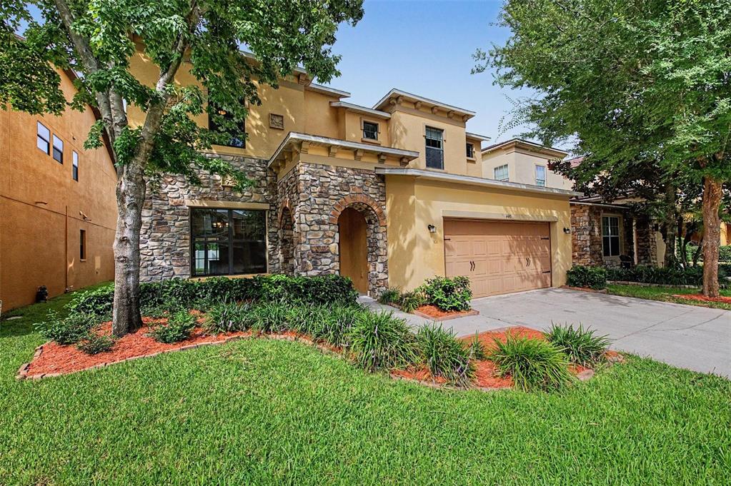 A two-story house with a stone facade, tan stucco walls, and an attached two-car garage — 440 WESTCHESTER HILLS LANE, VALRICO, FL
