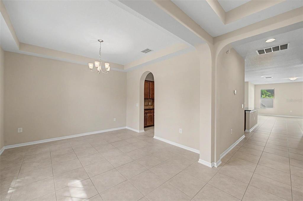 A dining room with tile flooring, a tray ceiling, and an arched doorway to the kitchen — 440 WESTCHESTER HILLS LANE, VALRICO, FL
