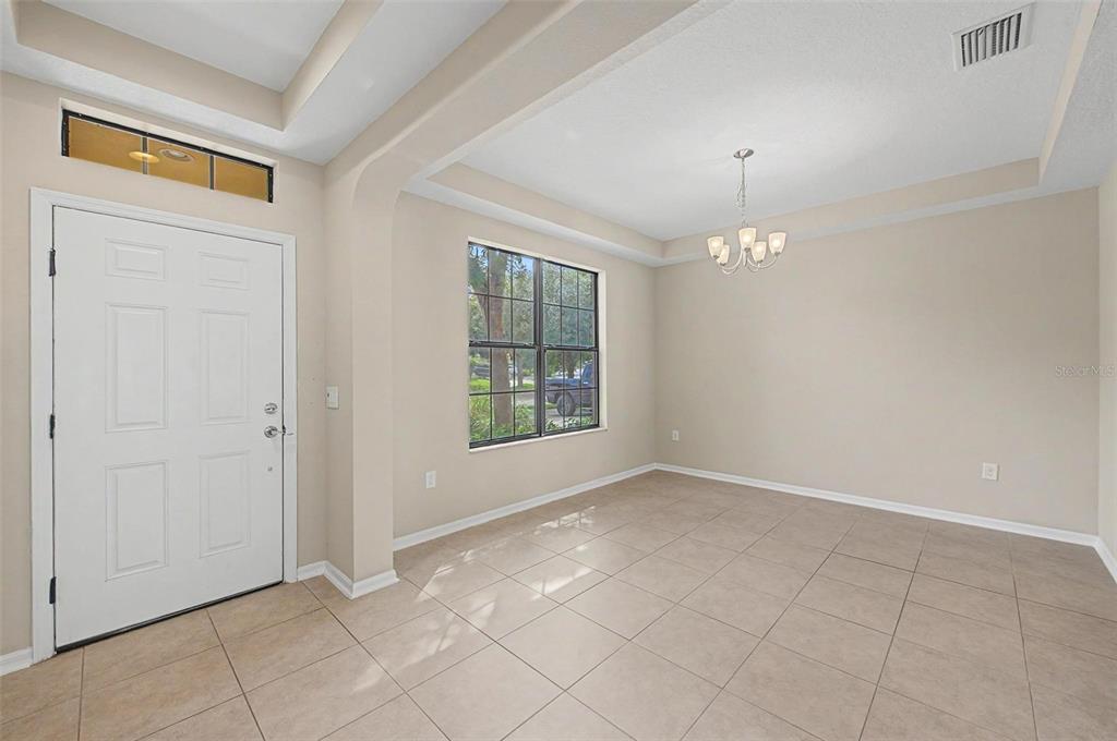 A bright dining room features tile flooring, a tray ceiling, and a chandelier — 440 WESTCHESTER HILLS LANE, VALRICO, FL
