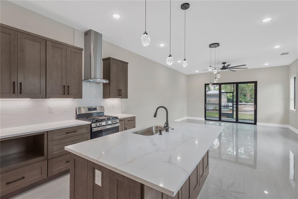 A modern kitchen features dark wood cabinets, a white quartz island, and a sliding glass door — 6021 INTERBAY UNIT 1, TAMPA, FL