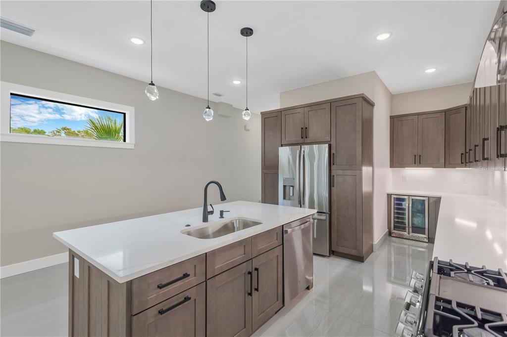 A modern kitchen features a large white island, stainless steel appliances, and dark wood cabinetry — 6021 INTERBAY UNIT 1, TAMPA, FL