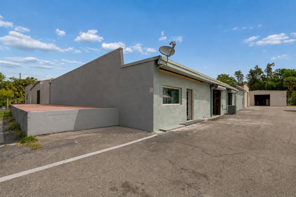 The exterior of a light-colored commercial building with a satellite dish and paved parking lot — 4214 W VIRGINIA AVE UNIT 11, TAMPA, FL