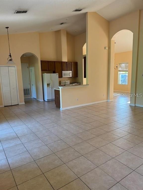 A kitchen with wood cabinets and a white refrigerator overlooks a tiled living area — 3321 PAWLEYS LOOP N, ST CLOUD, FL