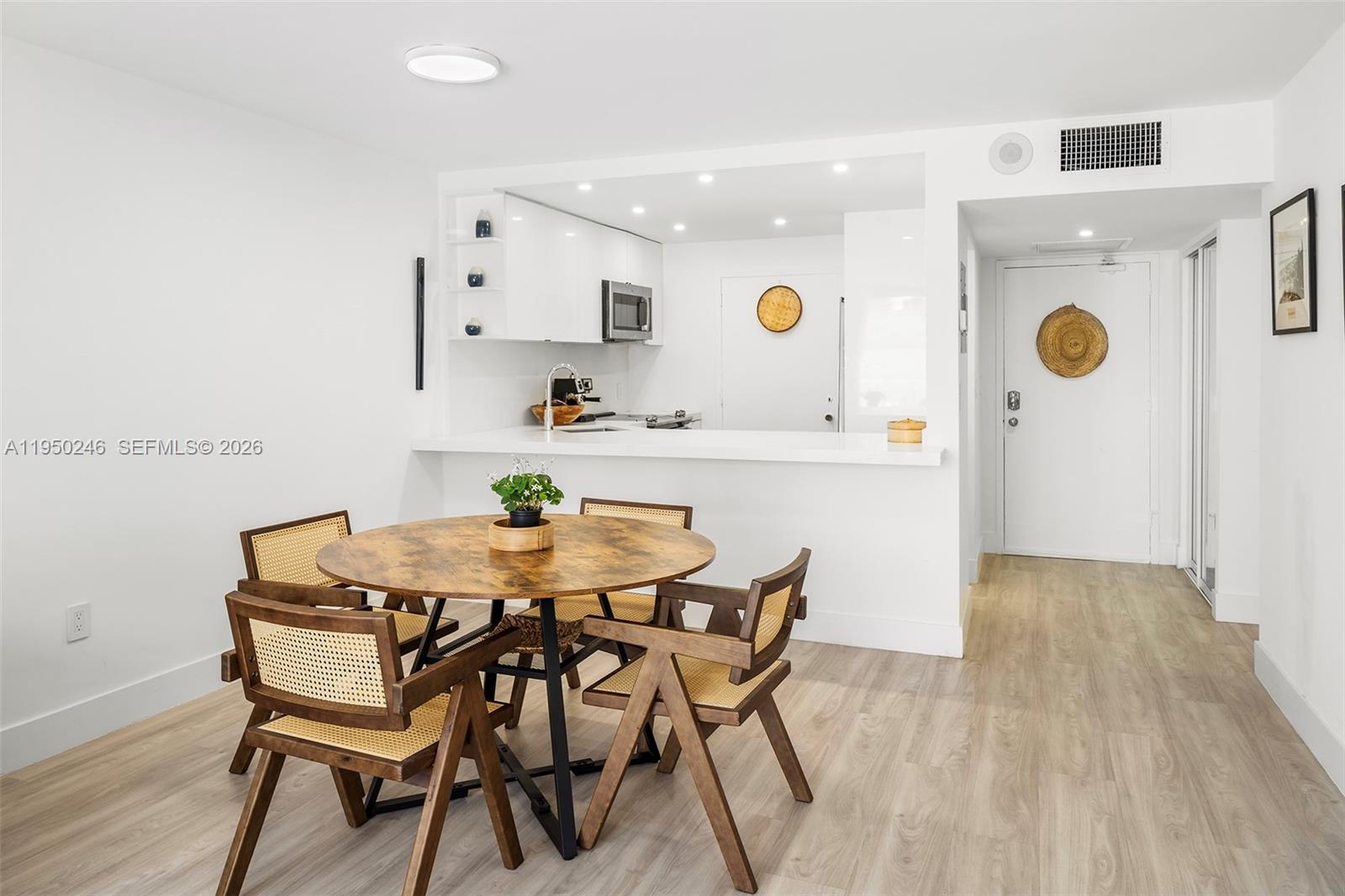 A dining area with a round wooden table and chairs sits before an open kitchen — 345 Ocean Dr # 610, Miami Beach FL 33139, MIAMI BEACH, FL