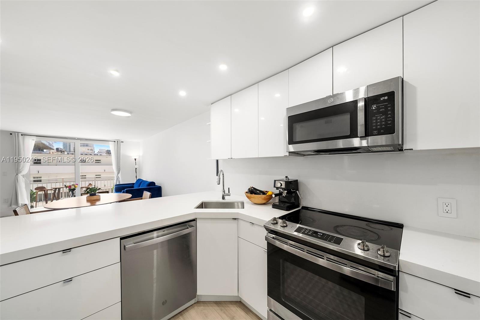 A modern kitchen features white cabinets, stainless steel appliances, and a view of a balcony — 345 Ocean Dr # 610, Miami Beach FL 33139, MIAMI BEACH, FL