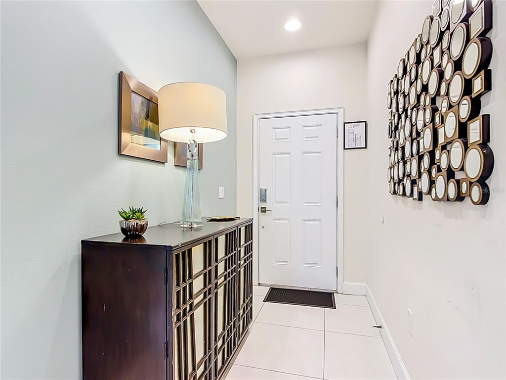 An entryway features a dark wood cabinet, a table lamp, and a wall-mounted mirror collage — 1433 RETREAT CIR, CLERMONT, FL