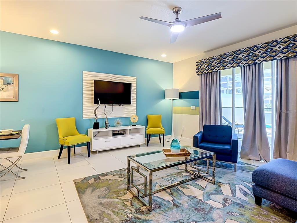 A living room features a blue accent wall, a glass coffee table, and yellow chairs — 1433 RETREAT CIR, CLERMONT, FL