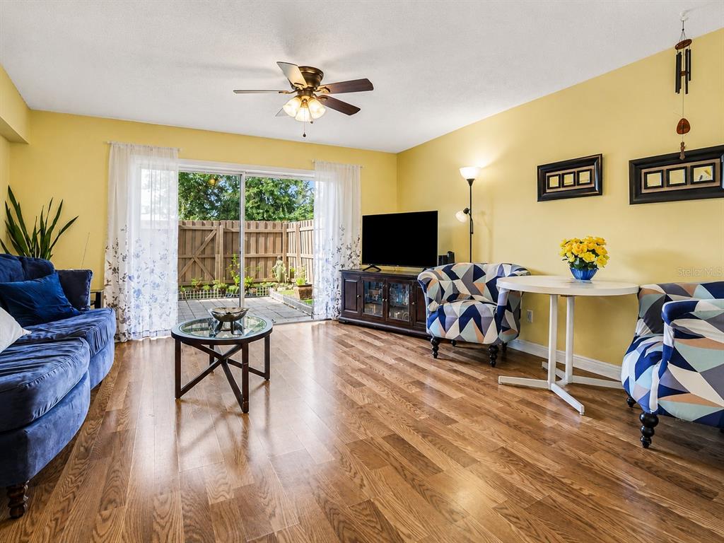 A living room features yellow walls, wood flooring, a blue sofa, and a sliding glass door — 120 GEORGETOWN DRIVE UNIT 120, CASSELBERRY, FL