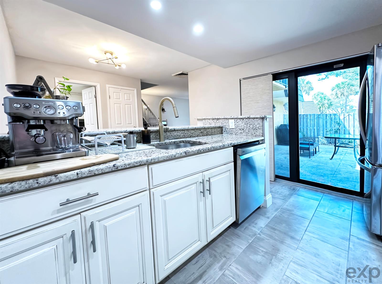 A kitchen features white cabinets, granite countertops, stainless steel appliances, and a sliding glass door — 1008 10th Way, West Palm Beach FL 33407, WEST PALM BEACH, FL
