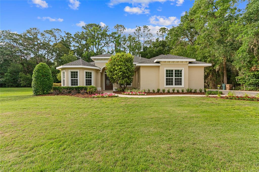 A single-story tan house with a dark roof sits on a large grassy lawn — 4117 SE 21ST STREET, OCALA, FL