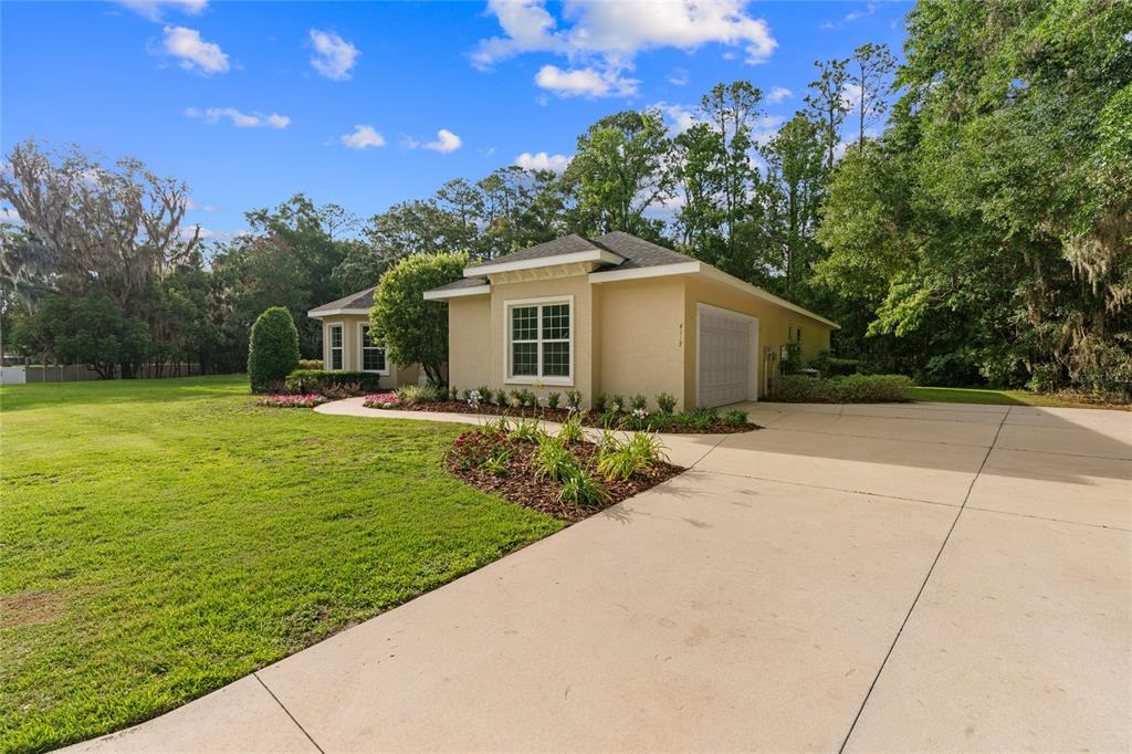 A tan single-story house with a concrete driveway and a large green lawn — 4117 SE 21ST STREET, OCALA, FL