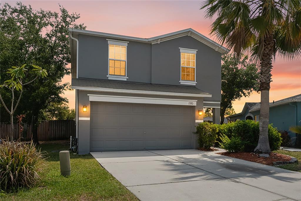 A two-story gray house with a two-car garage and a palm tree in the yard — 3533 CARDINAL FEATHER DRIVE, LAND O LAKES, FL