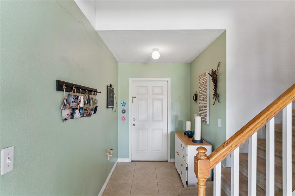 An entryway features light green walls, tile flooring, a white front door, and a staircase — 3533 CARDINAL FEATHER DRIVE, LAND O LAKES, FL