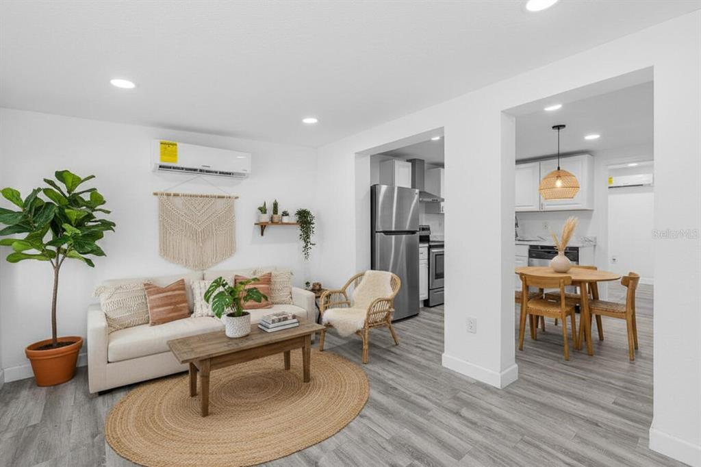 A living room with a sofa, coffee table, and rug opens into a kitchen area — 57 CABANA AVENUE, NORTH FORT MYERS, FL