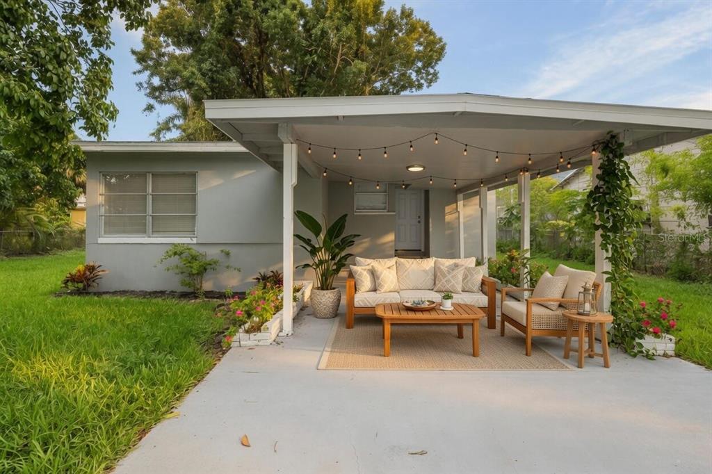 A covered patio features outdoor furniture, string lights, and a concrete floor in a backyard — 57 CABANA AVENUE, NORTH FORT MYERS, FL