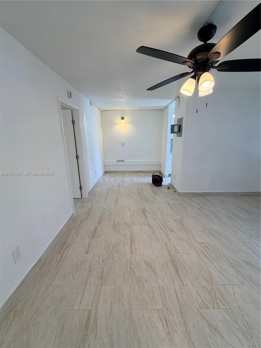 An empty room features light-colored wood-look tile flooring, white walls, and a ceiling fan — 220 NW 16th Ter # 1, Miami FL 33136, MIAMI, FL