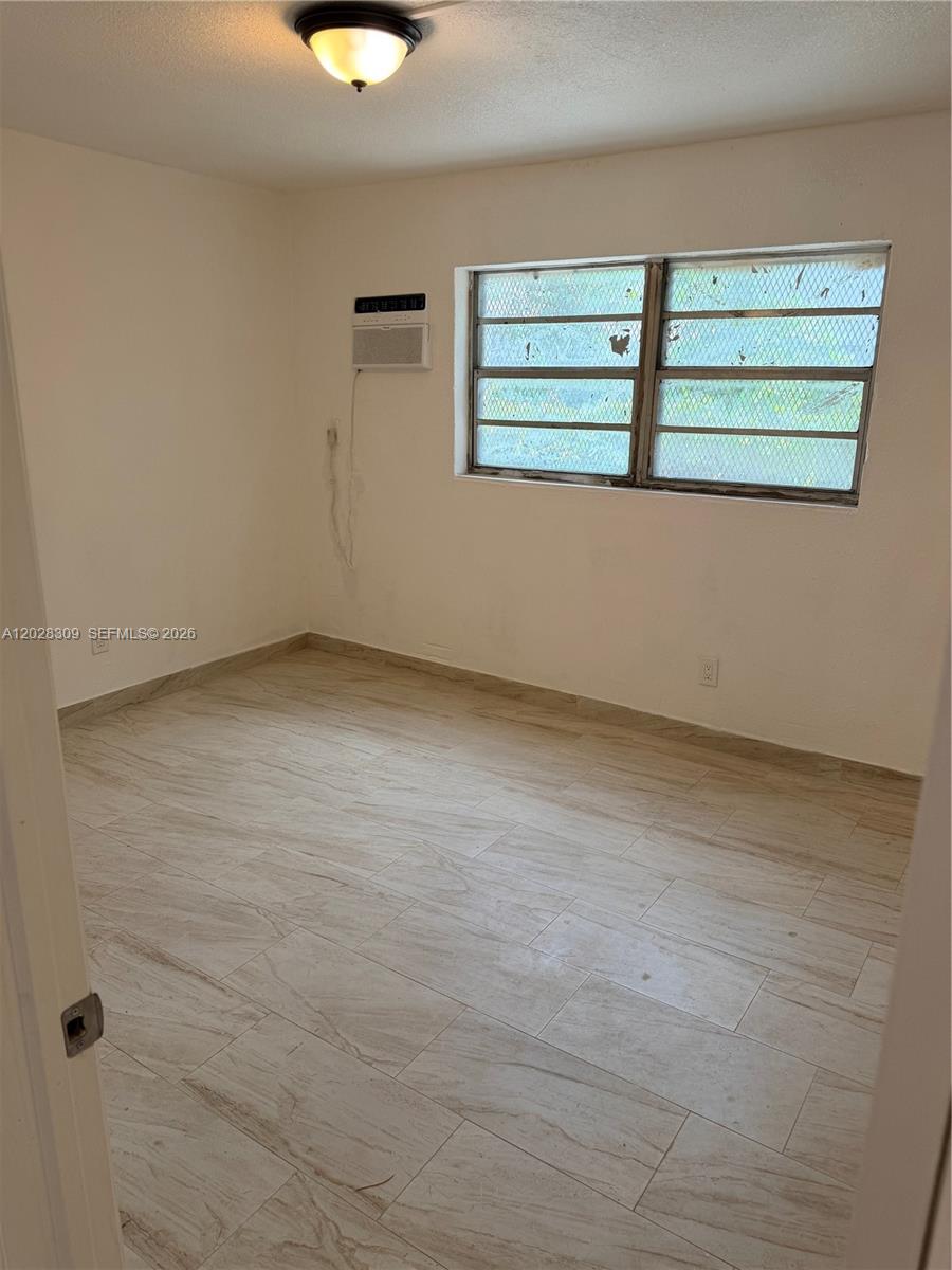 An empty bedroom features light-colored tile flooring, white walls, and a window air conditioner — 220 NW 16th Ter # 1, Miami FL 33136, MIAMI, FL