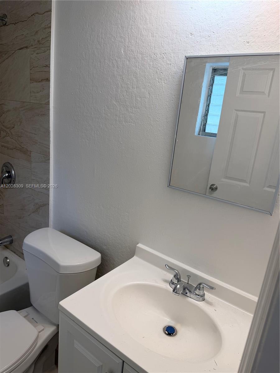 A bathroom features a white vanity, a toilet, and a tiled shower area — 220 NW 16th Ter # 1, Miami FL 33136, MIAMI, FL