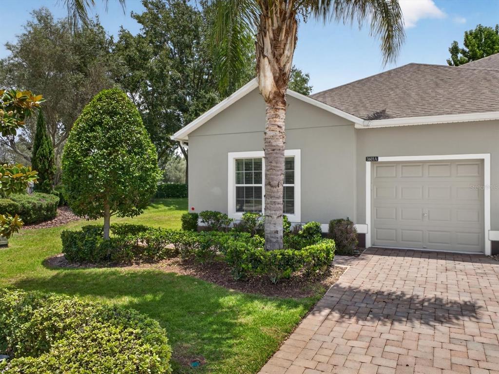 A single-story house exterior features a beige stucco facade, a paved driveway, and a garage — 3601 SOLANA CIRCLE UNIT A, CLERMONT, FL