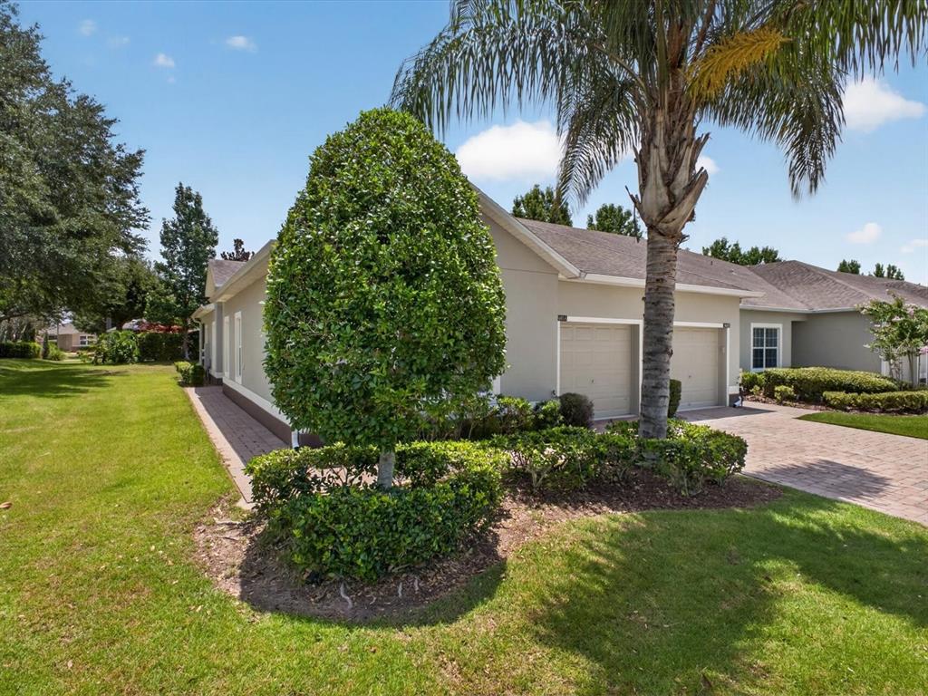 A tan house with a two-car garage, a palm tree, and manicured landscaping — 3601 SOLANA CIRCLE UNIT A, CLERMONT, FL