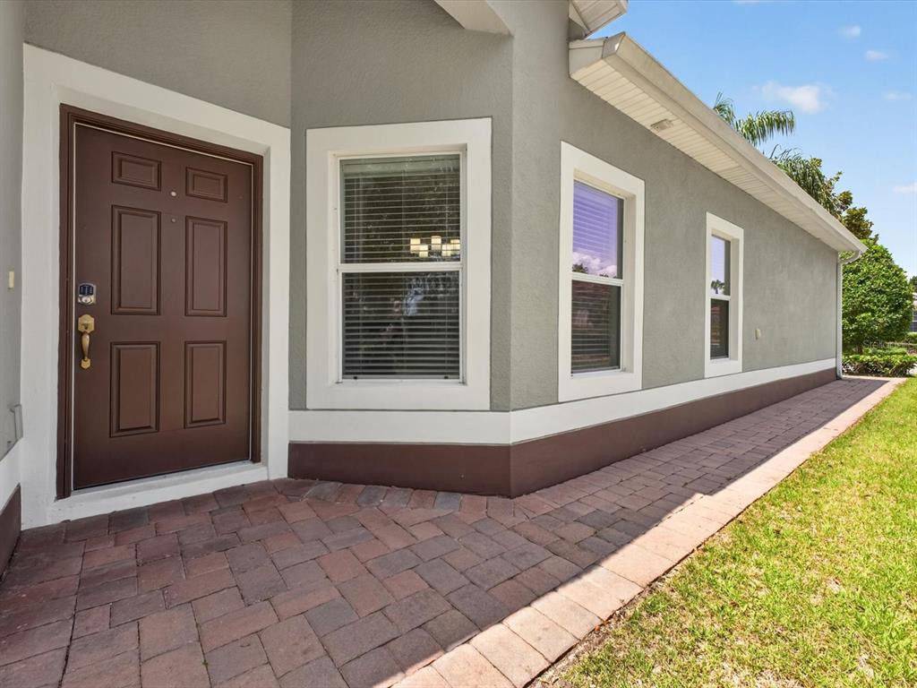 A brown front door and three windows on a gray house with a brick walkway — 3601 SOLANA CIRCLE UNIT A, CLERMONT, FL
