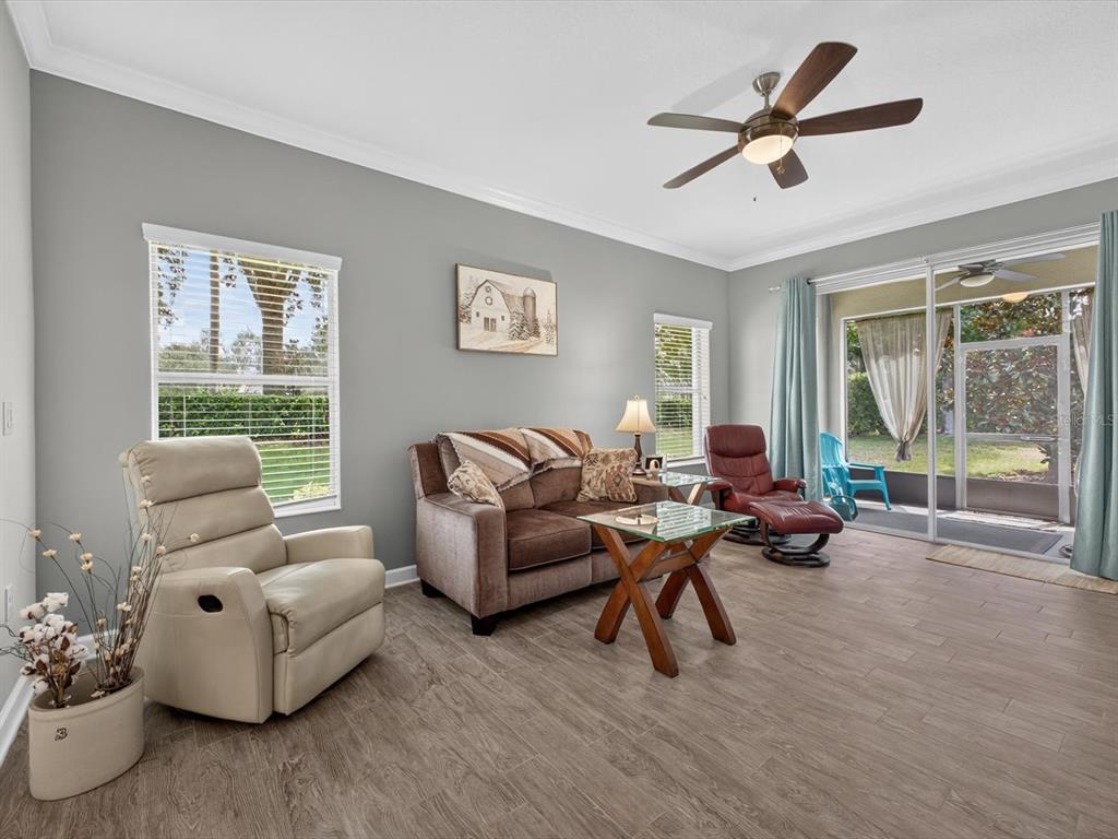 A living room features gray walls, wood-look tile flooring, a ceiling fan, and sliding glass doors — 3601 SOLANA CIRCLE UNIT A, CLERMONT, FL