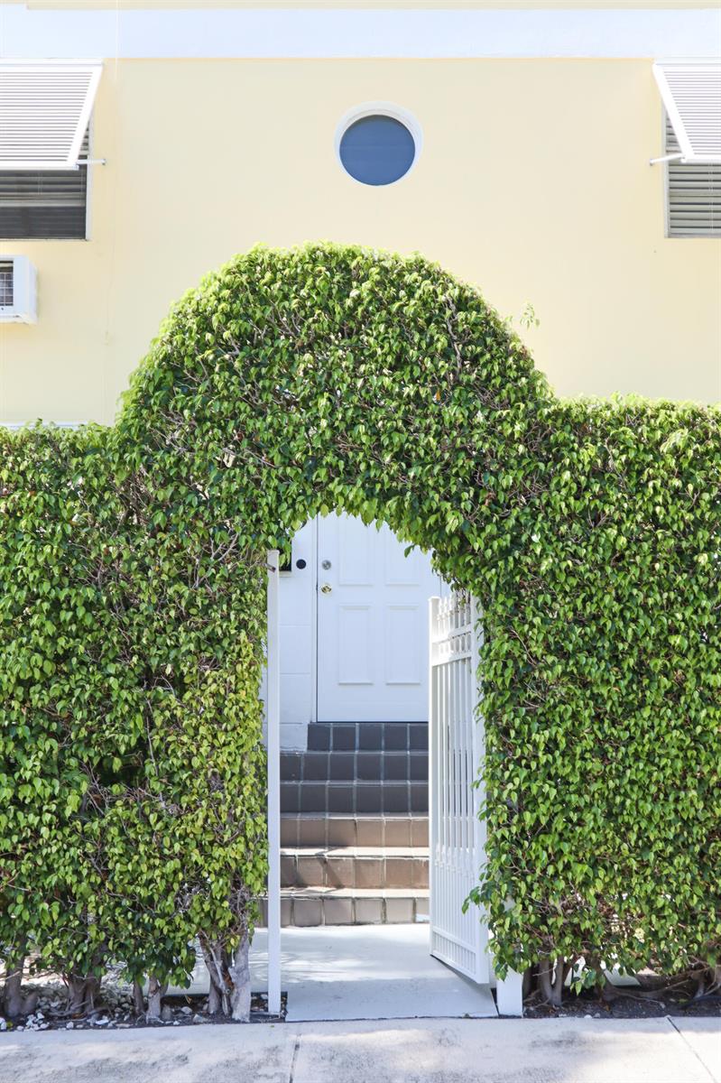 A white door with steps is visible through an arched hedge entryway in front of a building — 172 N County Road, Palm Beach FL 33480, PALM BEACH, FL