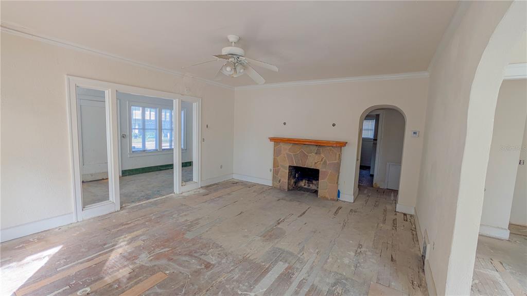 An empty living room features a stone fireplace, a ceiling fan, and exposed subflooring — 852 4TH AVENUE N, ST PETERSBURG, FL